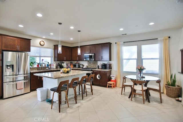 233 47th St, Long Beach, CA 90805 - kitchen with appliances with stainless steel finishes, recessed lighting, a center island, a breakfast bar area, and dark brown cabinetry