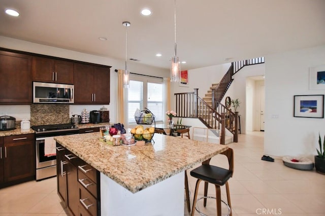 233 47th St, Long Beach, CA 90805 - kitchen with appliances with stainless steel finishes, a center island, tasteful backsplash, light stone counters, and light tile patterned flooring