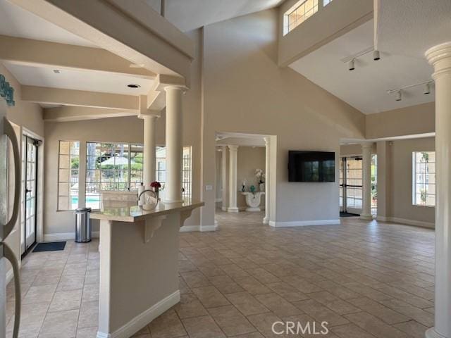 3211 Sello Ln Unit 100, Carlsbad, CA 92009 - kitchen with ornate columns, track lighting, a kitchen breakfast bar, open floor plan, and a towering ceiling