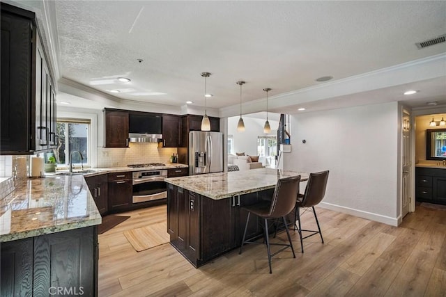 1205 Cerca, San Clemente, CA 92673 - kitchen featuring appliances with stainless steel finishes, crown molding, backsplash, a center island, and light stone counters