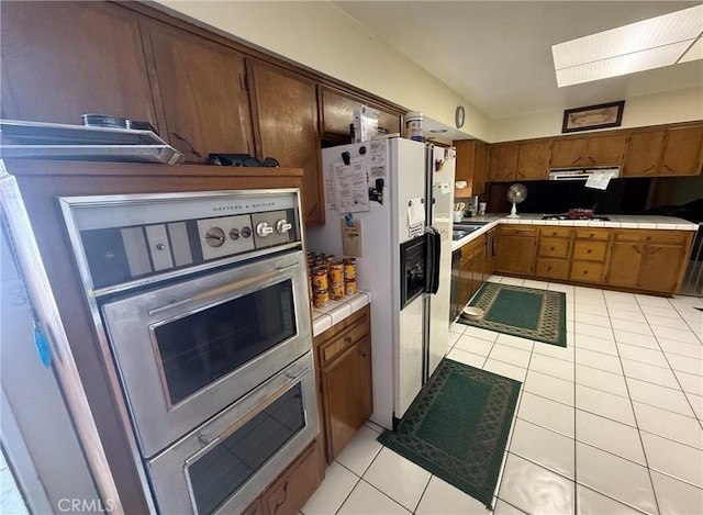 958 Berkshire Ct, Escondido, CA 92025 - kitchen with tile countertops, light tile patterned floors, under cabinet range hood, and white fridge with ice dispenser