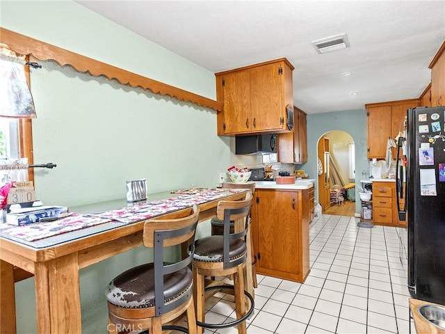 515 N Shelton St, Burbank, CA 91506 - kitchen featuring freestanding refrigerator, arched walkways, light tile patterned floors, brown cabinets, and light countertops