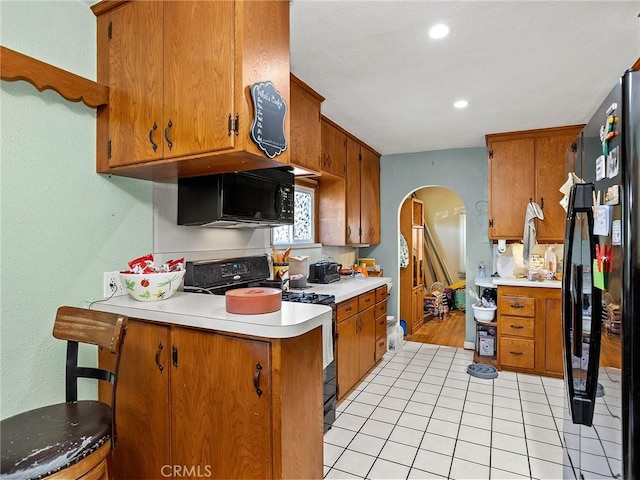 515 N Shelton St, Burbank, CA 91506 - kitchen with black appliances, arched walkways, light countertops, brown cabinetry, and a peninsula
