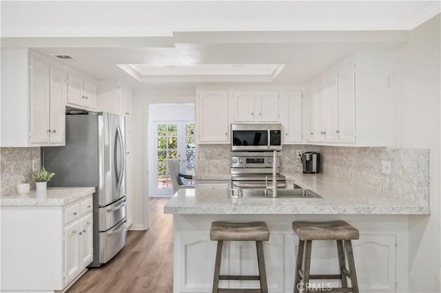 29282 Rue Cerise Unit 7, Laguna Niguel, CA 92677 - kitchen featuring stainless steel appliances, a peninsula, a tray ceiling, white cabinets, and light countertops