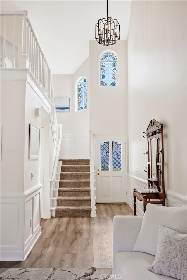 29282 Rue Cerise Unit 7, Laguna Niguel, CA 92677 - living room with a decorative wall, stairs, light wood-style floors, a chandelier, and a wainscoted wall