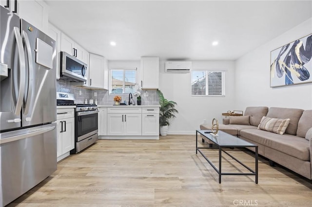 107 E Johnson St, Compton, CA 90220 - kitchen featuring stainless steel appliances, an AC wall unit, white cabinetry, tasteful backsplash, and open floor plan