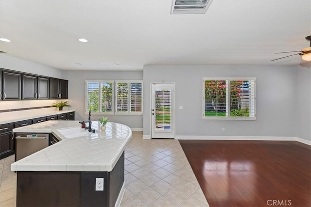 6701 Whitewater St, Eastvale, CA 91752 - kitchen featuring tile countertops, light tile patterned flooring, open floor plan, a kitchen island with sink, and recessed lighting