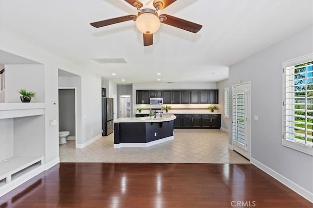 6701 Whitewater St, Eastvale, CA 91752 - kitchen with stainless steel microwave, freestanding refrigerator, light countertops, dark cabinets, and light tile patterned floors
