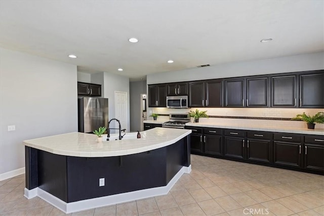 6701 Whitewater St, Eastvale, CA 91752 - kitchen with appliances with stainless steel finishes, decorative backsplash, an island with sink, dark cabinetry, and recessed lighting