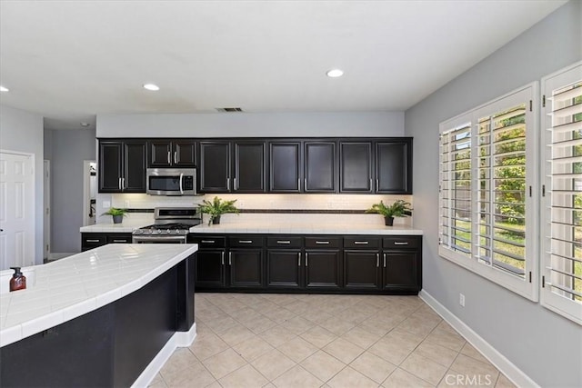6701 Whitewater St, Eastvale, CA 91752 - kitchen with appliances with stainless steel finishes, dark cabinetry, backsplash, tile counters, and recessed lighting