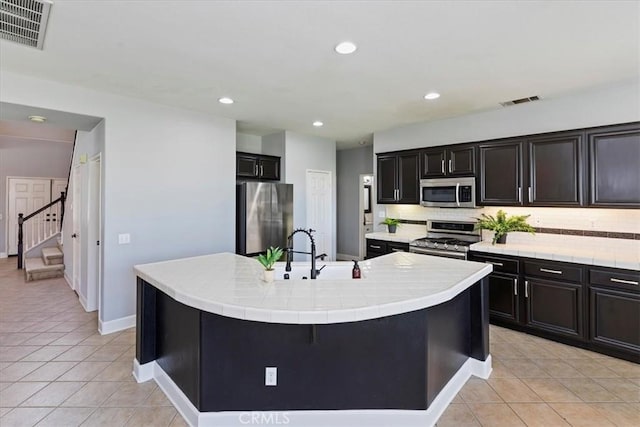 6701 Whitewater St, Eastvale, CA 91752 - kitchen with stainless steel appliances, light tile patterned floors, decorative backsplash, a center island with sink, and recessed lighting