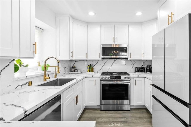 456 E San Jose Ave Unit C, Burbank, CA 91501 - kitchen featuring appliances with stainless steel finishes, white cabinetry, backsplash, light stone counters, and wood finished floors
