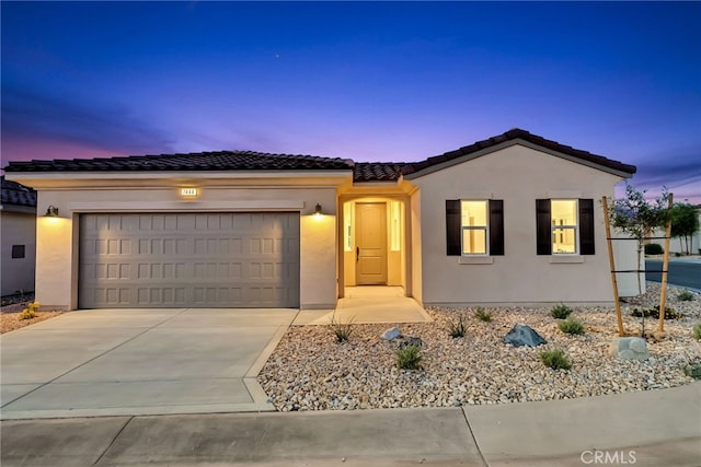 7444 Desert Sky Dr, Yucca Valley, CA 92284 - view of front facade featuring stucco siding, a garage, concrete driveway, and a tiled roof