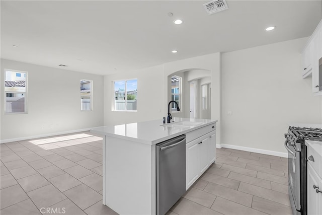 7444 Desert Sky Dr, Yucca Valley, CA 92284 - kitchen featuring appliances with stainless steel finishes, light tile patterned flooring, arched walkways, light countertops, and white cabinets