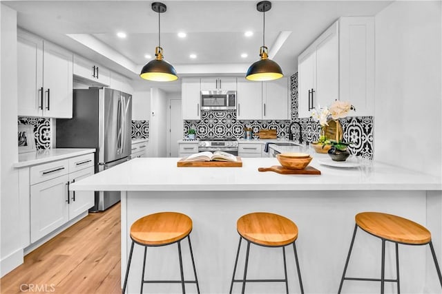 1059 Hillview Cir, Simi Valley, CA 93065 - kitchen featuring stainless steel appliances, a tray ceiling, recessed lighting, light wood-style floors, and a peninsula