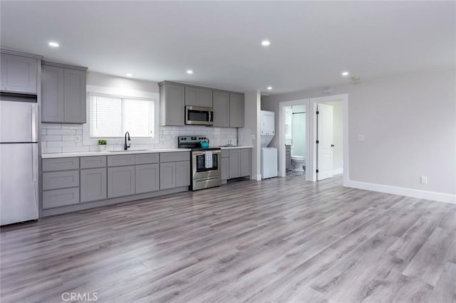 783 E Grand Ave, Pomona, CA 91766 - kitchen featuring appliances with stainless steel finishes, gray cabinetry, stacked washer and clothes dryer, backsplash, and recessed lighting