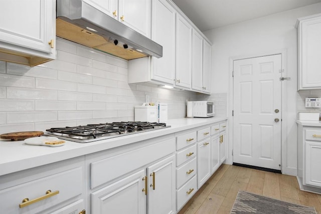 17236 Eagle Canyon Way, San Diego, CA 92127 - kitchen with under cabinet range hood, stainless steel gas stovetop, white cabinets, and light countertops