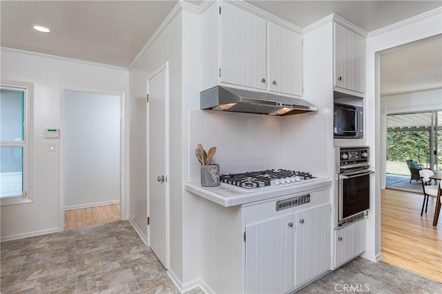 15713 Tuba St, North Hills, CA 91343 - kitchen with black oven, under cabinet range hood, white gas stovetop, tile counters, and decorative backsplash