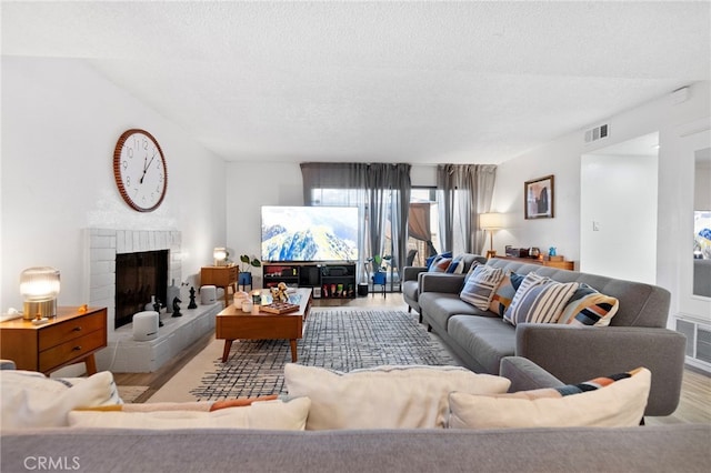 1110 Ohio Ave Unit 107, Long Beach, CA 90804 - living area with wood finished floors, a brick fireplace, and a textured ceiling
