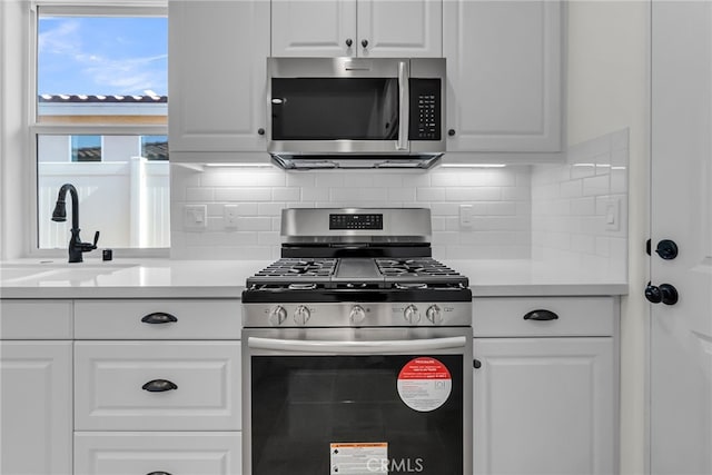 7432 Desert Sky Dr, Yucca Valley, CA 92284 - kitchen with stainless steel appliances, white cabinetry, backsplash, and light countertops