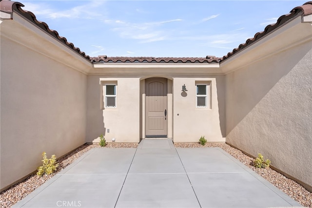 7432 Desert Sky Dr, Yucca Valley, CA 92284 - property entrance featuring stucco siding, a tile roof, and a patio area