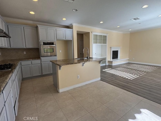 14610 Baylor Ave, Chino, CA 91710 - kitchen featuring oven, light tile patterned flooring, ornamental molding, dark stone counters, and gray cabinets