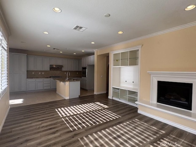 14610 Baylor Ave, Chino, CA 91710 - kitchen featuring black oven, a kitchen island with sink, crown molding, wood finished floors, and stovetop