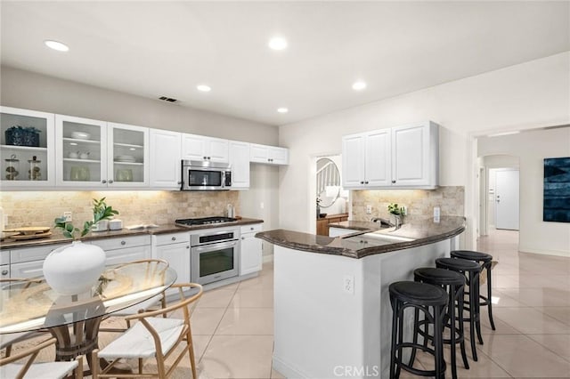 52 Anjou, Newport Coast, CA 92657 - kitchen with stainless steel appliances, dark countertops, light tile patterned floors, a breakfast bar, and tasteful backsplash