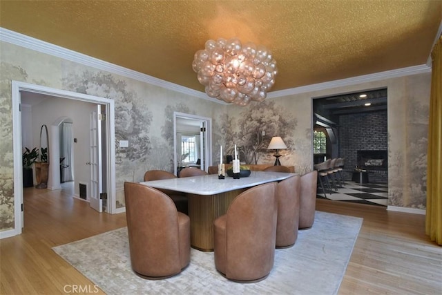 5005 Los Feliz Blvd, Los Angeles, CA 90027 - dining area featuring wood finished floors, ornamental molding, a brick fireplace, arched walkways, and wallpapered walls