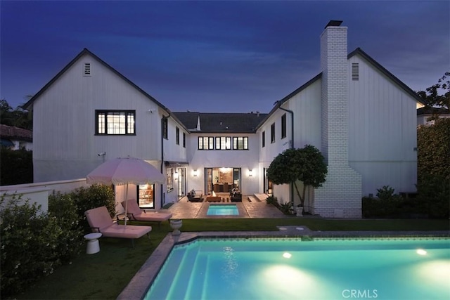 5005 Los Feliz Blvd, Los Angeles, CA 90027 - back of house at night with a chimney, an outdoor hangout area, an outdoor pool, a patio, and a yard