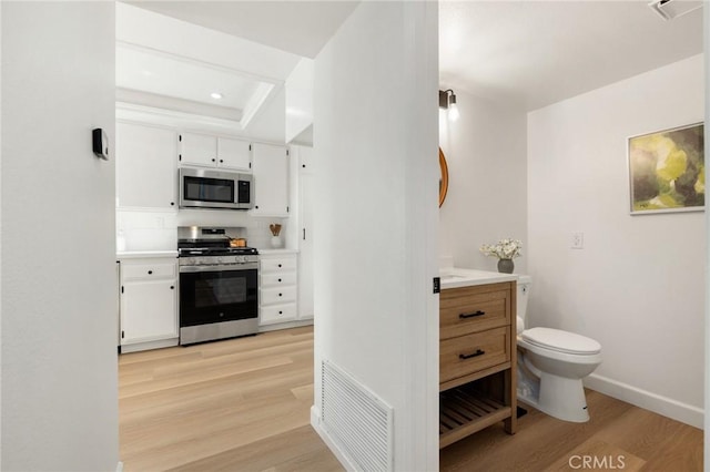 754 Manecita Cir, Perris, CA 92571 - kitchen featuring stainless steel appliances, light wood-style floors, white cabinetry, light countertops, and a tray ceiling