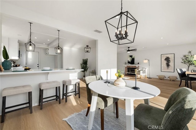 754 Manecita Cir, Perris, CA 92571 - dining space featuring light wood-style flooring, ceiling fan, a chandelier, a brick fireplace, and recessed lighting