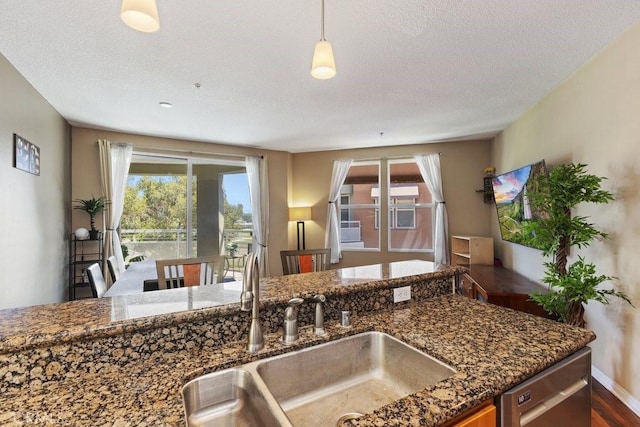 12688 Chapman Ave Unit 3403, Garden Grove, CA 92840 - kitchen with healthy amount of natural light, dark stone countertops, a textured ceiling, stainless steel dishwasher, and hanging light fixtures