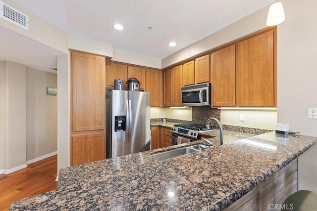 12688 Chapman Ave Unit 3403, Garden Grove, CA 92840 - kitchen featuring stainless steel appliances, wood finished floors, dark stone countertops, brown cabinets, and recessed lighting