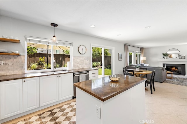 42 Beech Dr, Aliso Viejo, CA 92656 - kitchen with dishwasher, a glass covered fireplace, decorative backsplash, white cabinets, and pendant lighting