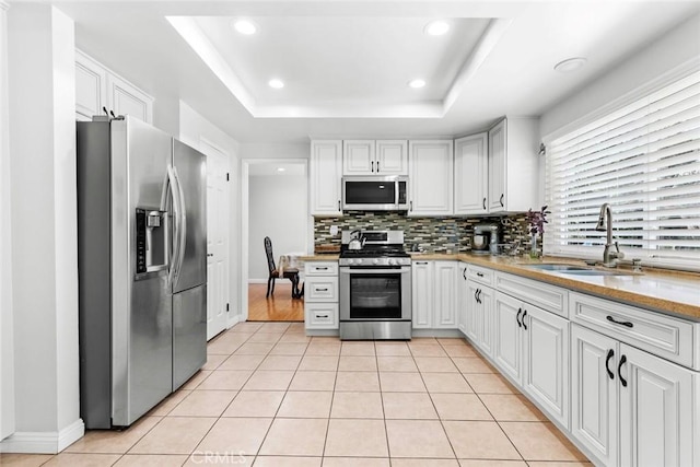 20623 Russ Jay St, Saugus, CA 91350 - kitchen featuring appliances with stainless steel finishes, decorative backsplash, light tile patterned flooring, light countertops, and a tray ceiling