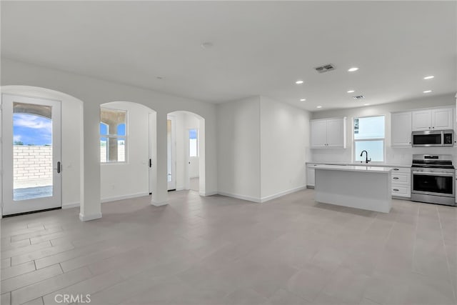 7420 Desert Sky Dr, Yucca Valley, CA 92284 - kitchen with appliances with stainless steel finishes, open floor plan, arched walkways, light countertops, and a center island