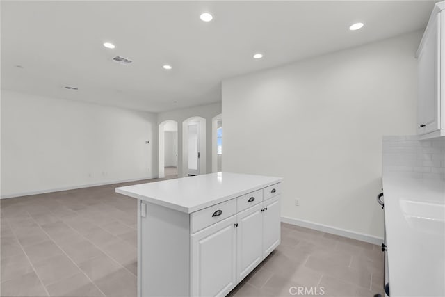 7420 Desert Sky Dr, Yucca Valley, CA 92284 - kitchen featuring arched walkways, recessed lighting, white cabinetry, light countertops, and a center island