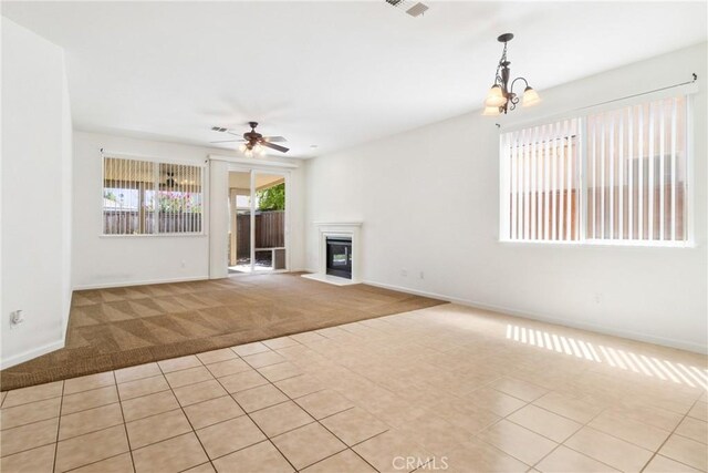 6631 Aggies Ct, Winton, CA 95388 - unfurnished living room featuring carpet floors, a ceiling fan, a chandelier, a fireplace with flush hearth, and tile patterned floors