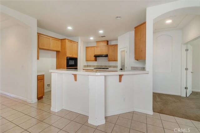 6631 Aggies Ct, Winton, CA 95388 - kitchen with black microwave, under cabinet range hood, a peninsula, light countertops, and a breakfast bar