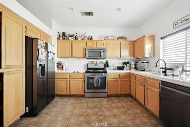 25780 Jumano Dr, Moreno Valley, CA 92551 - kitchen with stainless steel appliances, light tile patterned flooring, tile counters, and light brown cabinetry