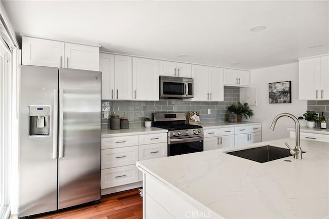 312 N Francisca Ave Unit 1, Redondo Beach, CA 90277 - kitchen with appliances with stainless steel finishes, backsplash, white cabinetry, light wood-type flooring, and light stone counters