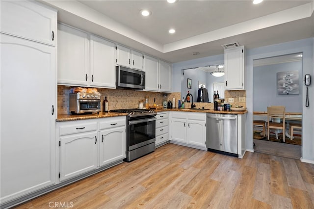 42821 15th St W Unit 4, Lancaster, CA 93534 - kitchen with stainless steel appliances, white cabinets, recessed lighting, decorative backsplash, and light wood-type flooring