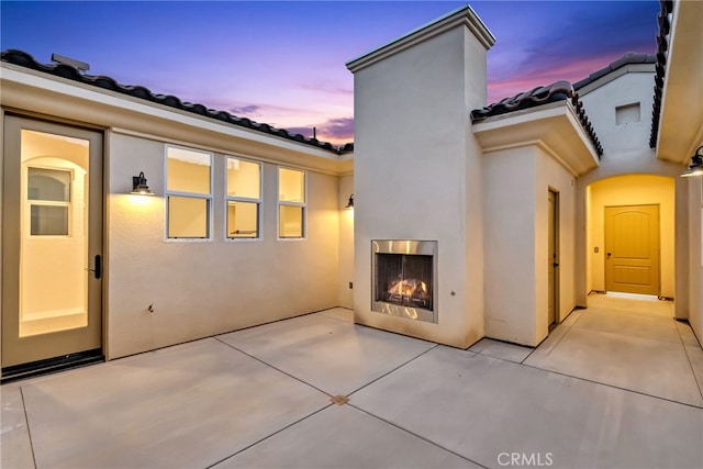 7408 Desert Sky Dr, Yucca Valley, CA 92284 - back of property with a lit fireplace, a patio, stucco siding, and a tiled roof