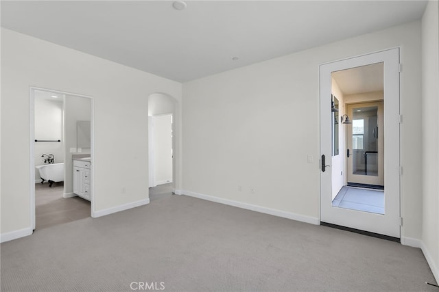 7408 Desert Sky Dr, Yucca Valley, CA 92284 - unfurnished bedroom with light carpet, arched walkways, and ensuite bath