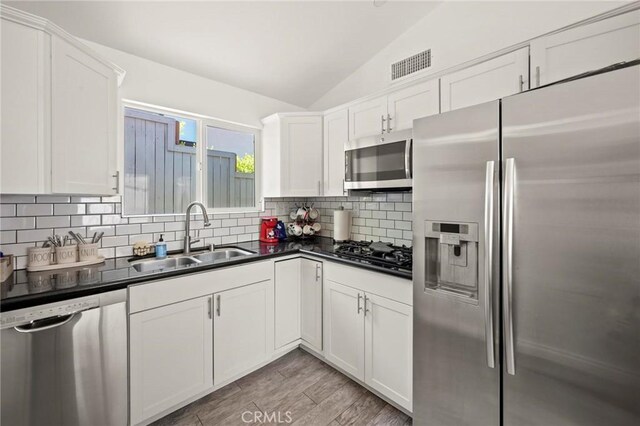3532 Mesquite Dr, Calabasas, CA 91302 - kitchen with stainless steel appliances, dark countertops, white cabinetry, decorative backsplash, and vaulted ceiling