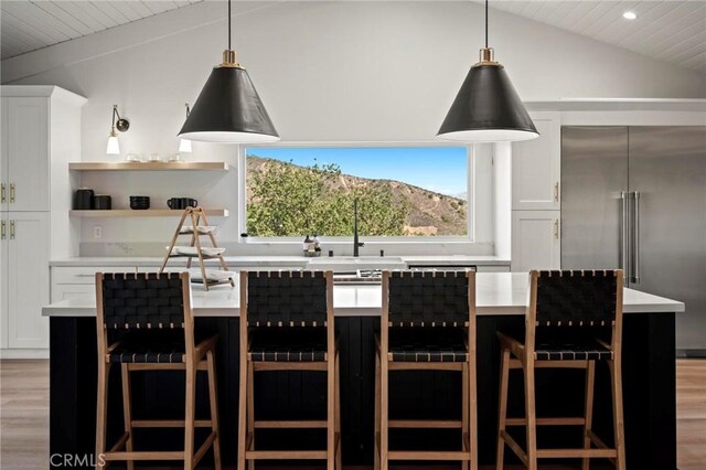 3532 Mesquite Dr, Calabasas, CA 91302 - kitchen with built in refrigerator, light wood-style floors, vaulted ceiling, light countertops, and white cabinetry