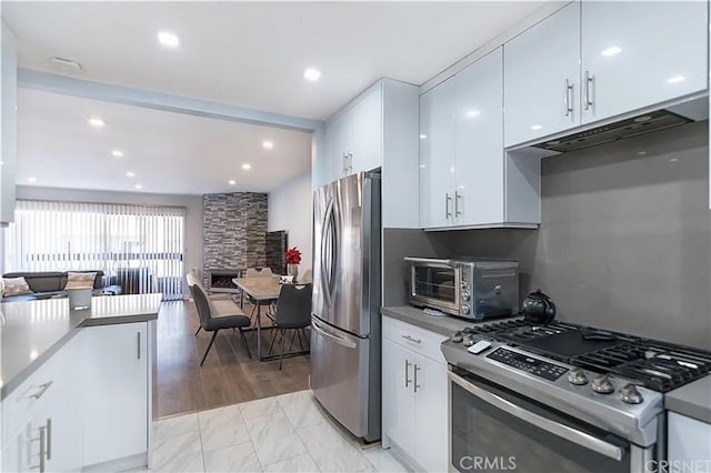 1236 N Columbus Ave Unit 28, Glendale, CA 91202 - kitchen featuring stainless steel appliances, under cabinet range hood, white cabinetry, open floor plan, and light marble finish flooring