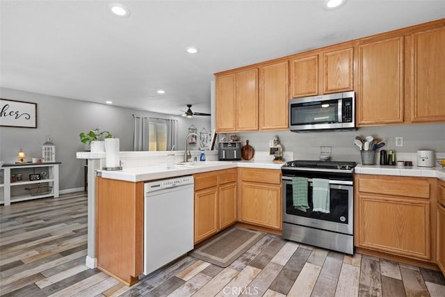 23317 Badger Creek Ln, Menifee, CA 92587 - kitchen with stainless steel appliances, a peninsula, light wood-style floors, ceiling fan, and recessed lighting