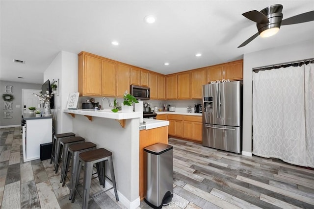 23317 Badger Creek Ln, Menifee, CA 92587 - kitchen featuring stainless steel appliances, a peninsula, light countertops, a breakfast bar, and a ceiling fan